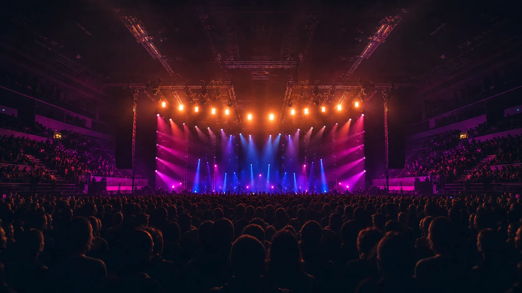 Palco envolvido por luzes magenta, azul e âmbar diante da plateia